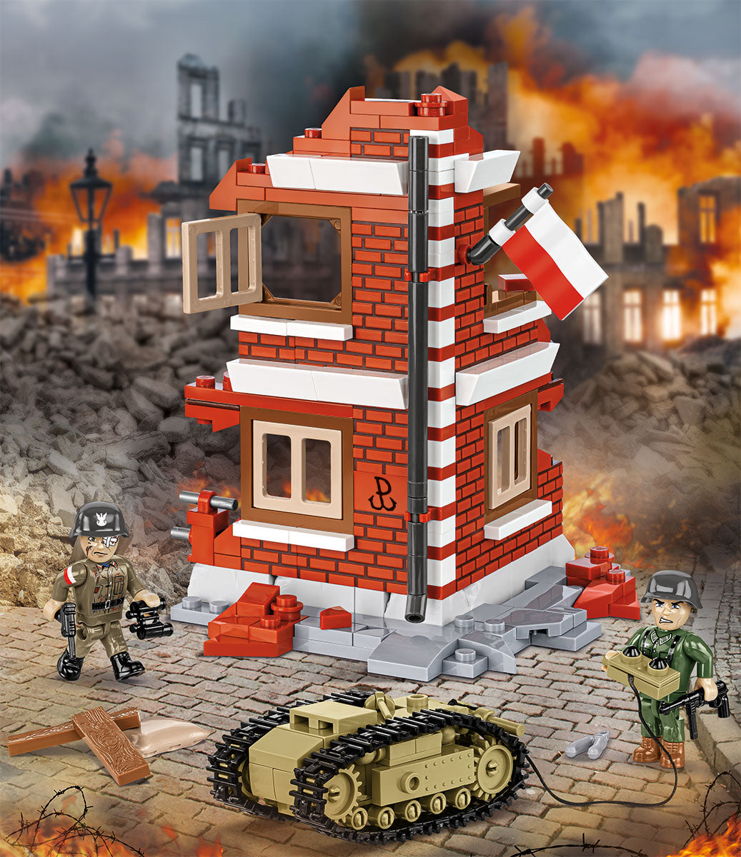 Un set de bloques de construcción de juguete que representa un edificio de ladrillo rojo y blanco con una bandera polaca, rodeado de dos minifiguras de soldados, un tanque color arena y una escena de ciudad devastada por la guerra al fondo.
